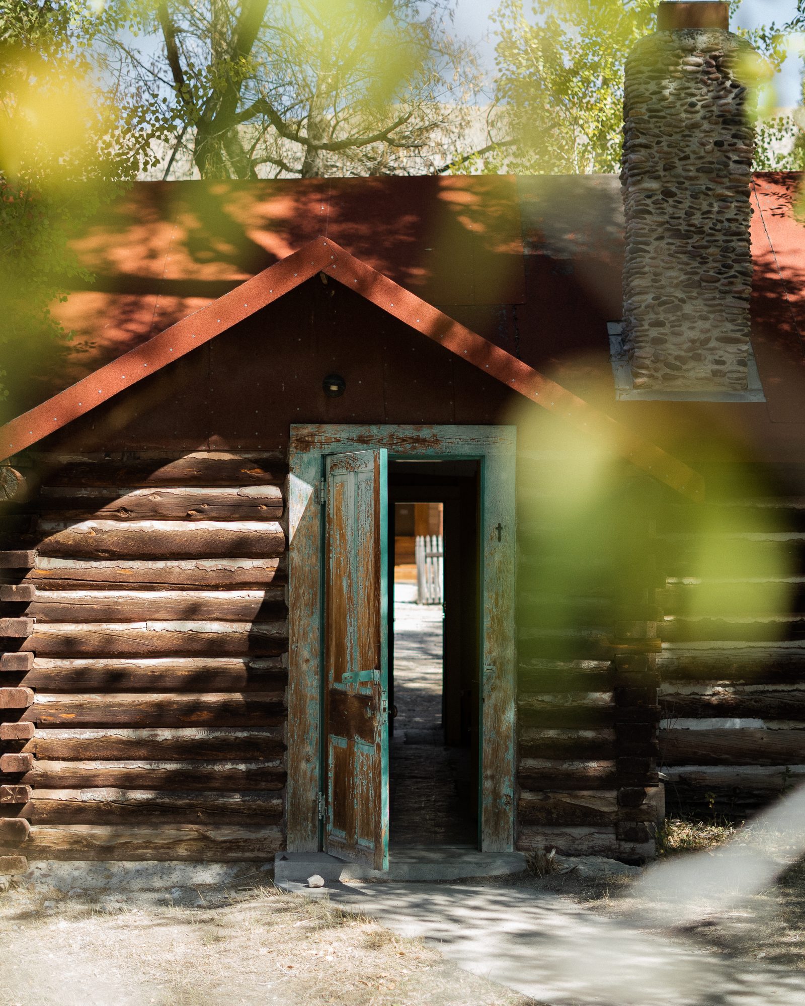 Weathered log cabin with an open turquoise door