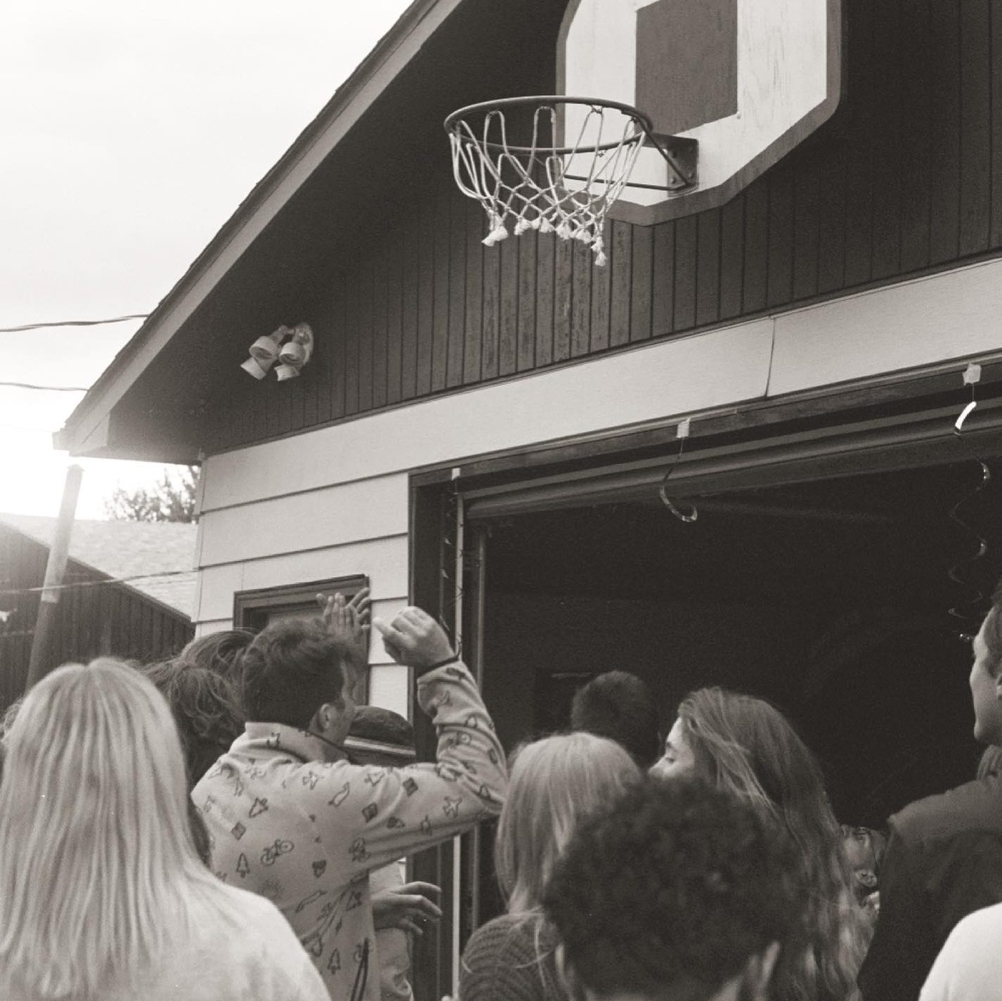 Crowd watching a basketball hoop on a garage, black and white