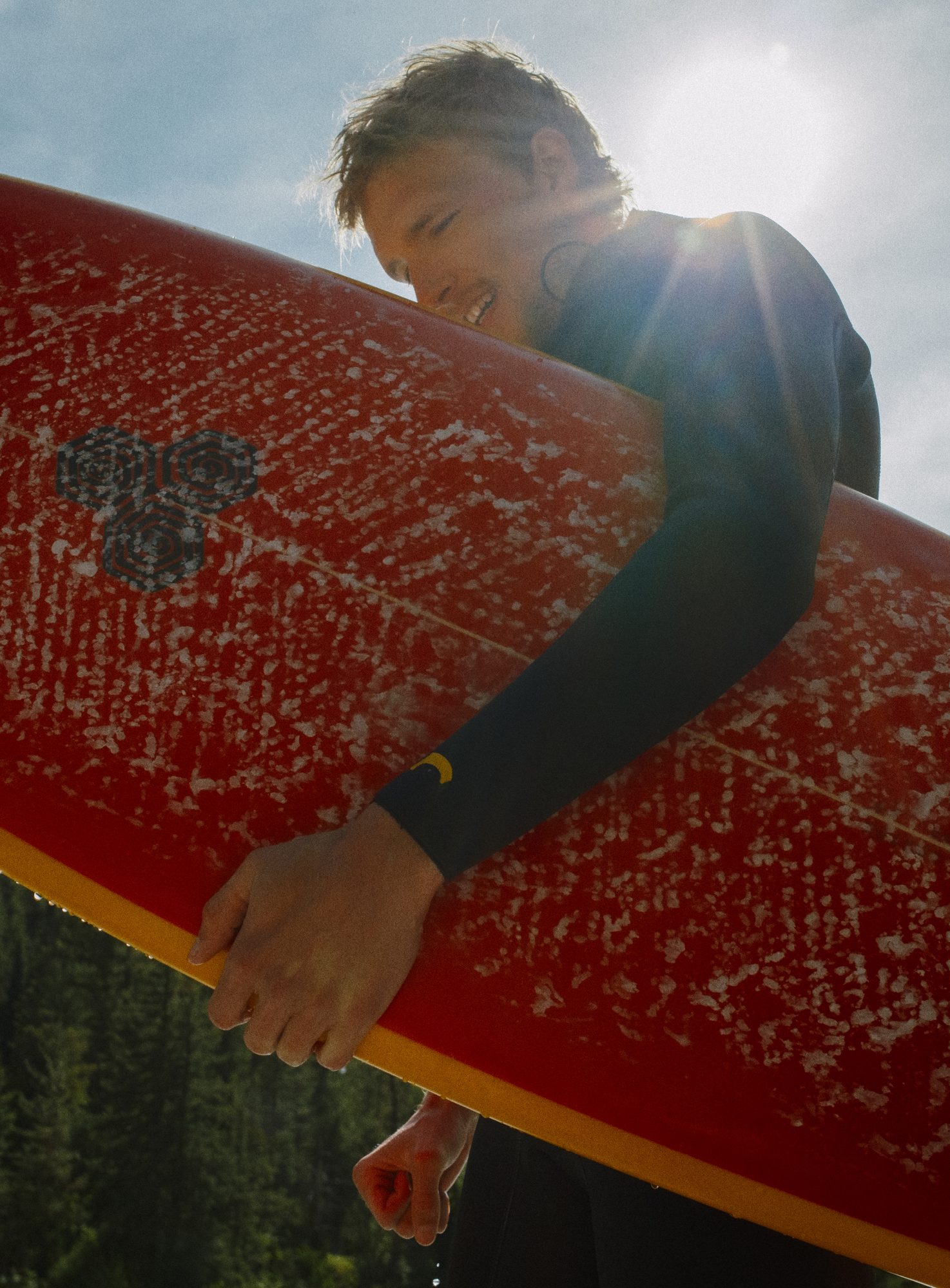 Surfer carrying a red board against the sun